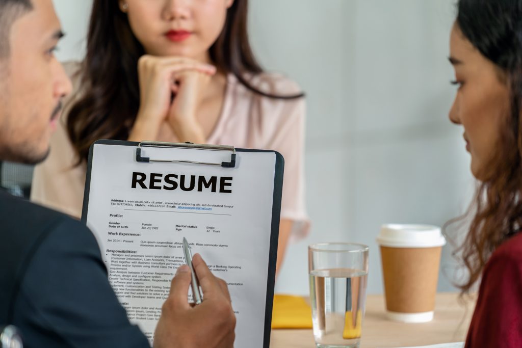 Interview process for business consultancy services in Dubai, with a candidate's resume being reviewed by consultants in a professional setting.